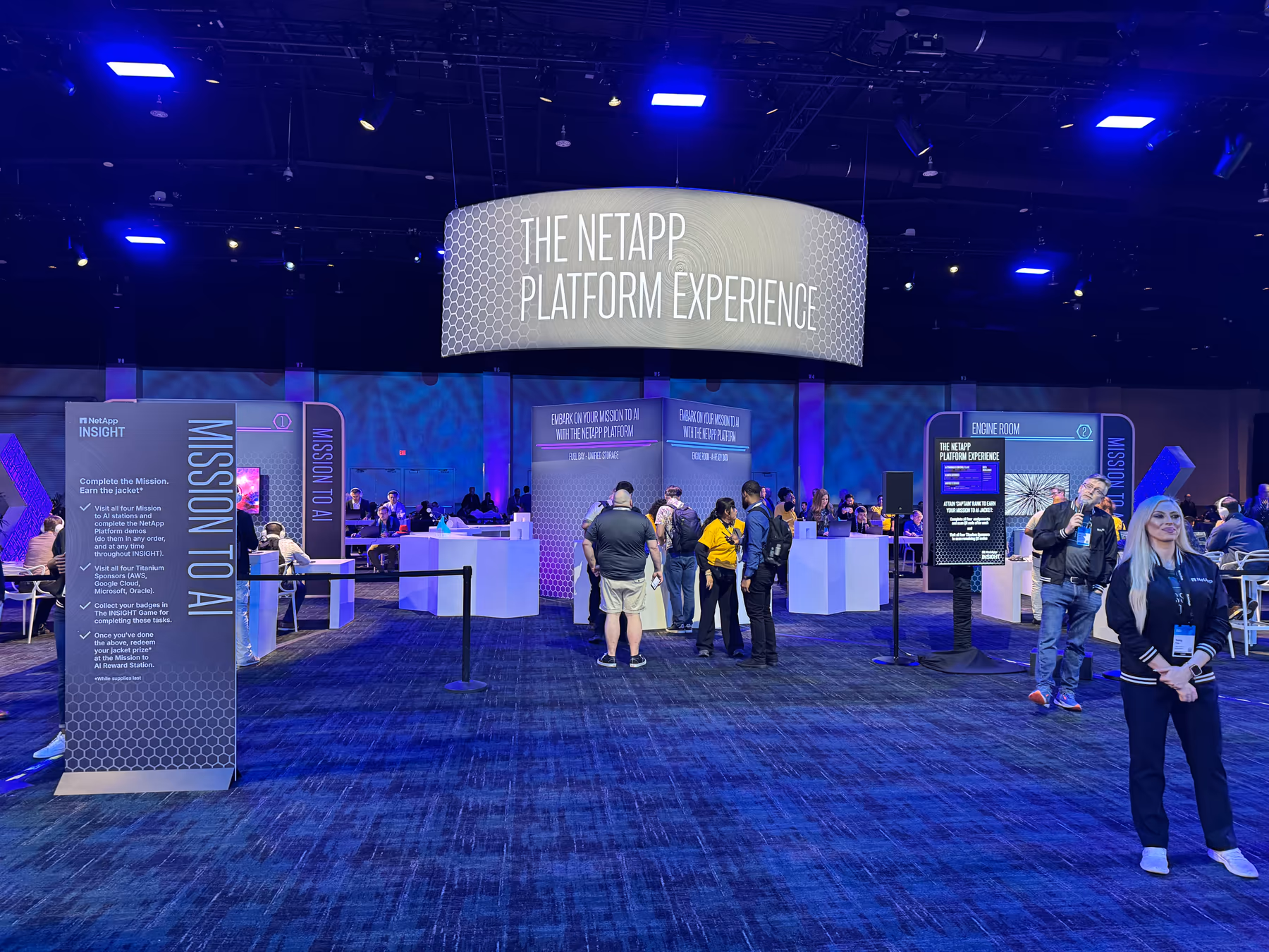 The NetApp Platform Experience at NetApp INSIGHT 2026, with a circular overhead sign, Mission to AI station panels, and attendees on the show floor